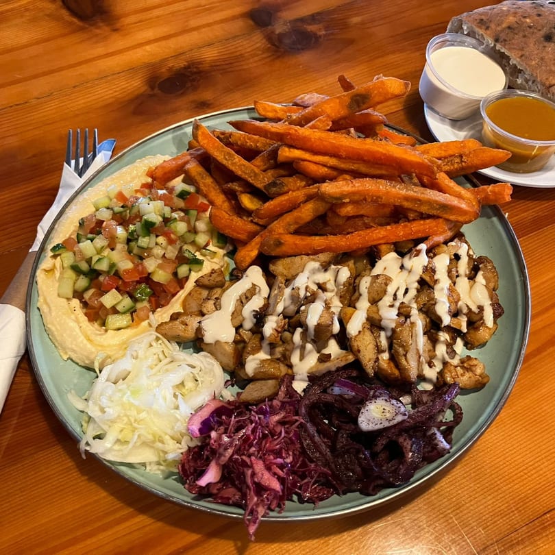 A Gili's Kitchen kosher shawarma platter with chicken, hummus, salad, sweet potato fries, and cabbage.